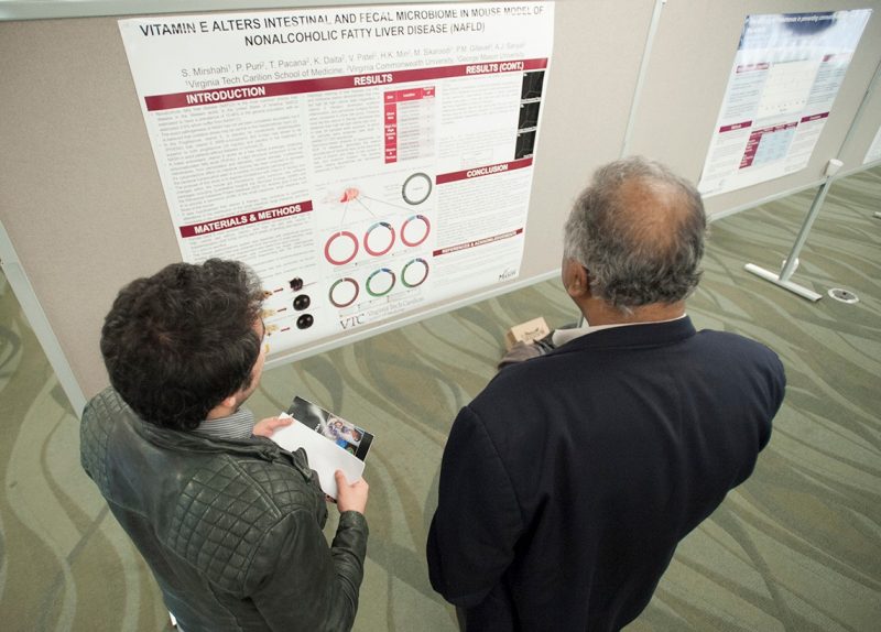 student Shervin Mirshahi examines his research project poster with his advisor, Dr. Puneet Puri.