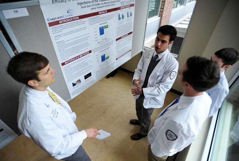 Four medical students discuss a poster presentation. 