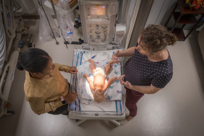 Early Identification Program Participant and Principle Investigator stand over a simulation doll in the Center for Simulation