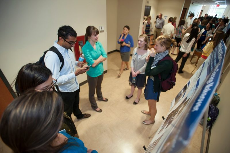 Students and visitors browse the service learning project posters.