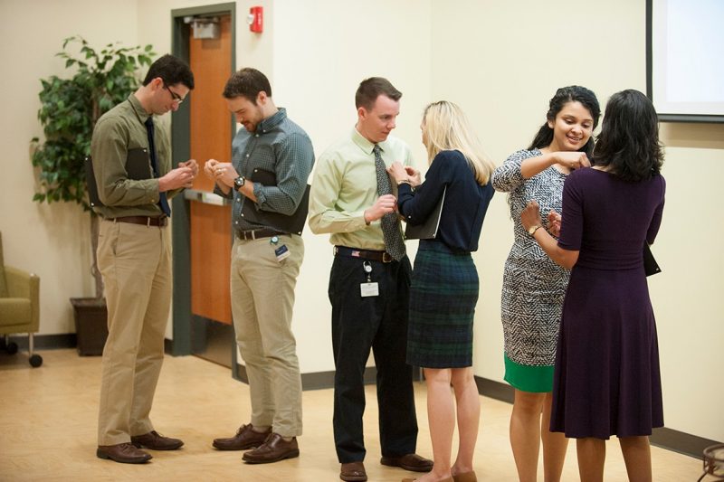 Medical students place pins on each other after being inducted into the Gold Humanism Honor Society.
