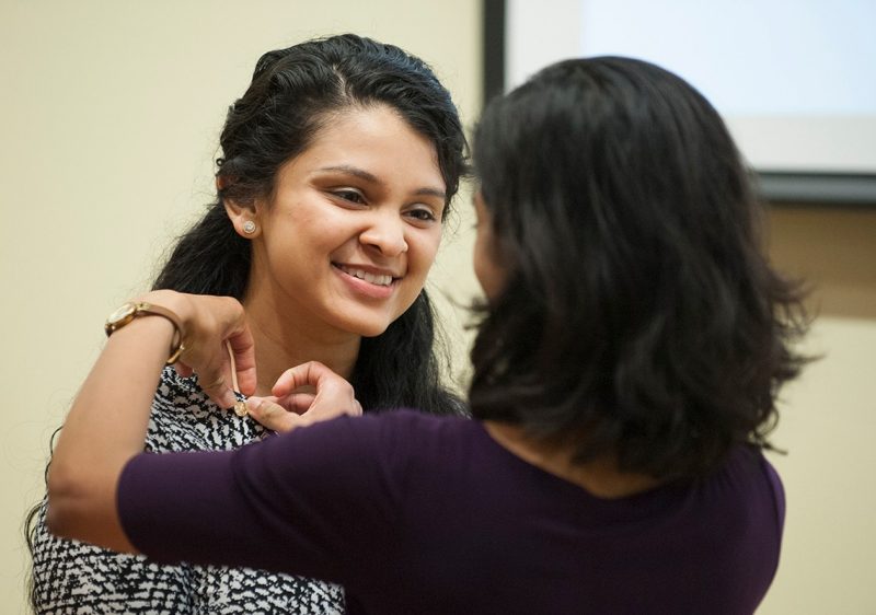 Tarangi Sutaria (left) has a pin placed on her by Silpa Thaivalappil as part of the induction ceremony into the Gold Humanism Honor Society.
