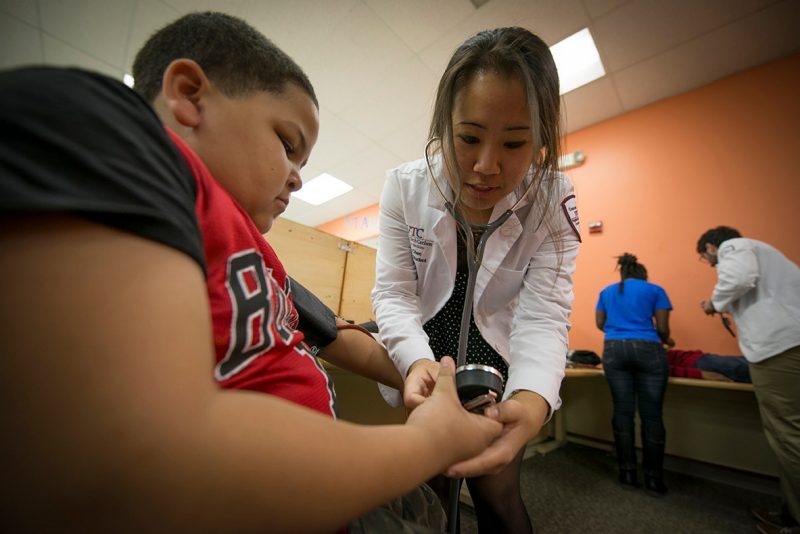 Judy Chen demonstrates how to take a blood pressure reading on a member of the Boys and Girls Club.