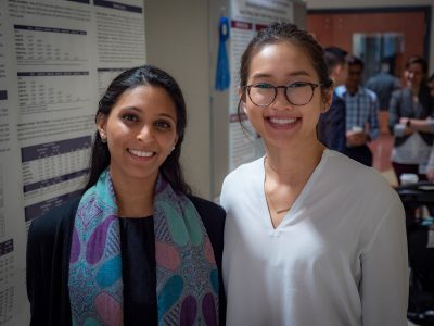 Two women smiling with two scientific posters in background
