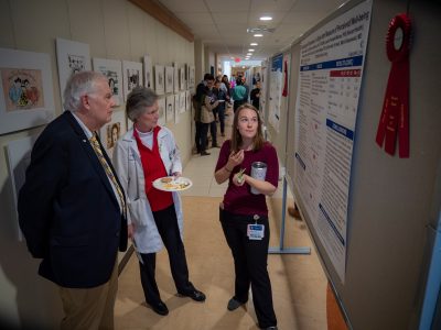 Man and woman listening to another woman explain her scientific poster