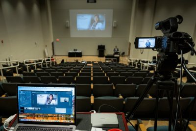 View from back of mostly empty auditorium with laptop computer and video equipment in foreground