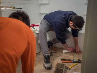 2 volunteers working on tiled floor in bathroom