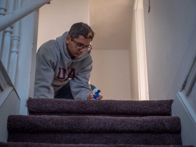 volunteer cleaning the carpet at the top of the stairs