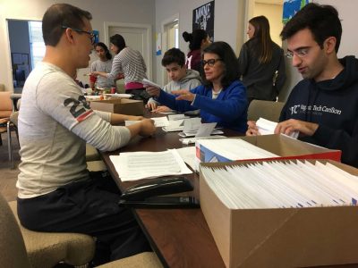 volunteers sitting at a table stuffing envelopes