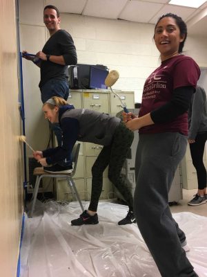 three students painting the renovation alliance wall