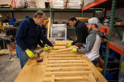 Dean Learman, staff member Dustin Womack and two volunteers laying out the lumber for a ramp component