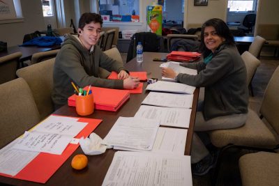 Faculty member Helena Carvalho and student creating information packets for the Roanoke community members