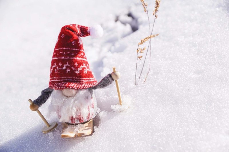 Dwarf Gnome wearing a red hat, walking on Snow with skis