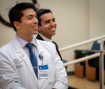 Medical students Jean Sabile and Malek Bouzaher standing and smiling at front of auditorium.