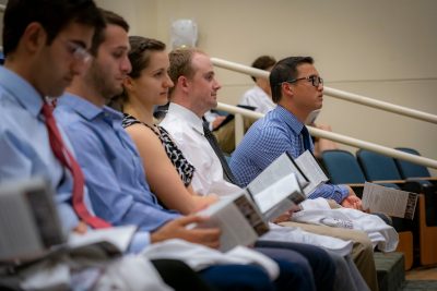 Five medical students seated in a row in an auditorium listening to a presentation