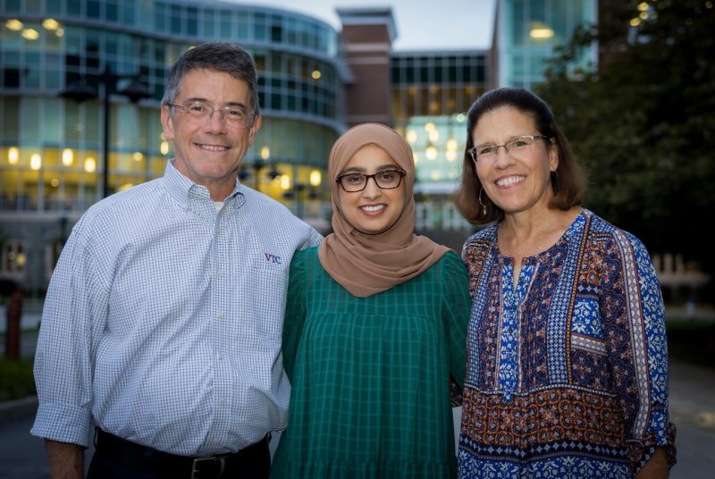 Woman wearing hijab flanked by male and female mentors.