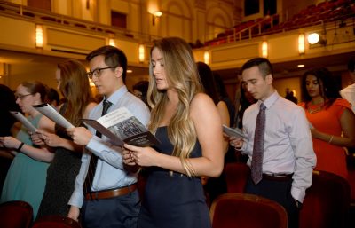 VTCSOM first-year student stand as a group and recite the Hippocratic Oath from their White Coat Ceremony programs.
