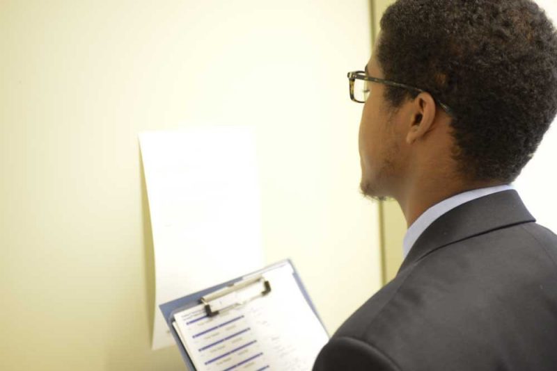 prospective student holding a clipboard, reading instructions on the wall as part of MMI weekend