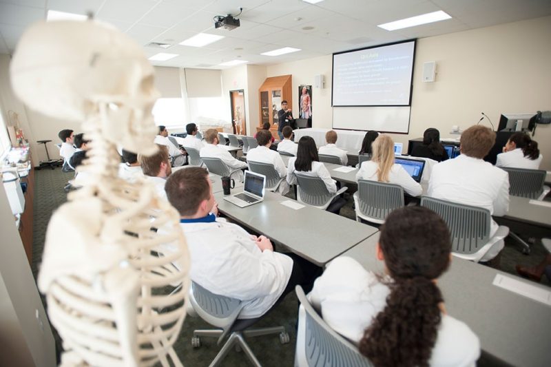 VTCSOM Classroom showing a skeleton along with students in white coats viewing a presentation