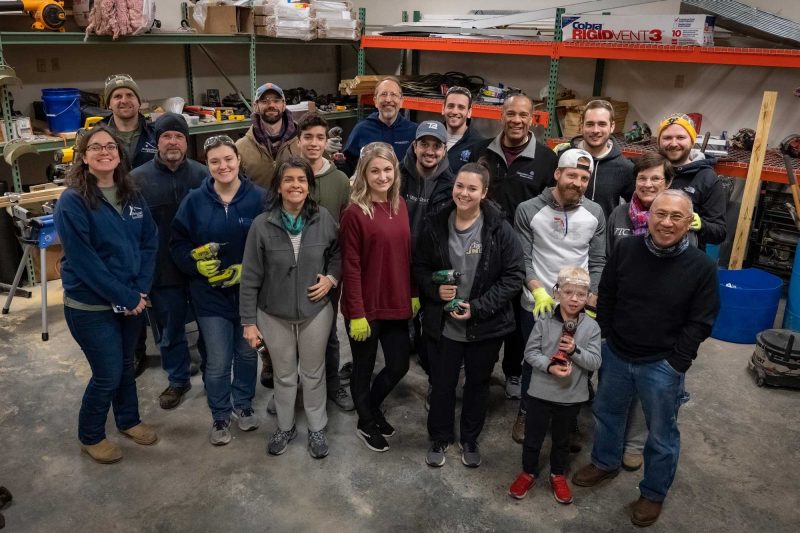 Group of 17 volunteers, including Dean Lee Learman and Senior Associate Dean for Diversity, Inclusion, and Student Vitality N.L. Bishop pose for a group photo in the Renovation Alliance workshop