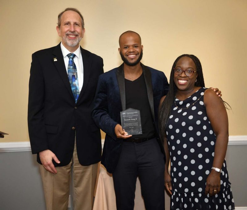 Three individuals stand together smiling with the Dean's Diversity Champion Award.