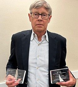 Man holding two awards