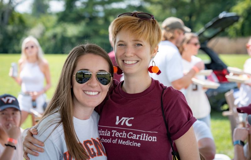 Two students smile a the VTCSOM tailgate in 2021.