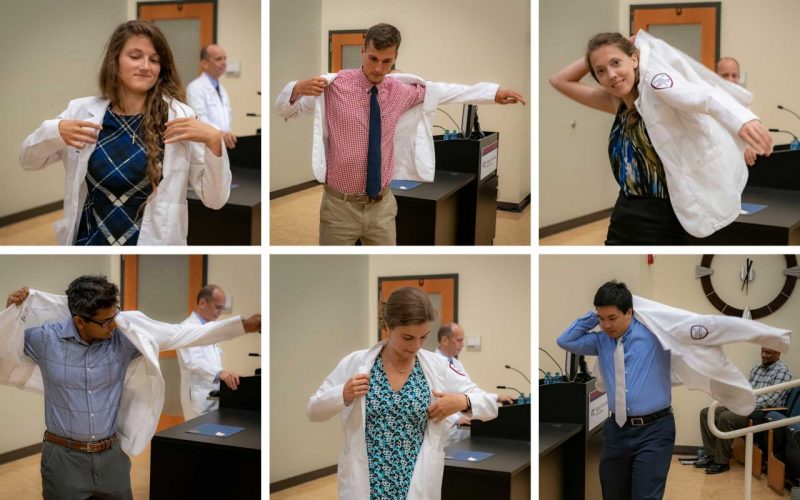 six students donning their own white coats during clinician ceremony