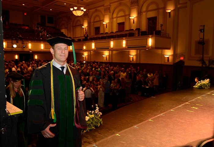 Graduate Scott Dart gives a thumbs up as he takes the stage.