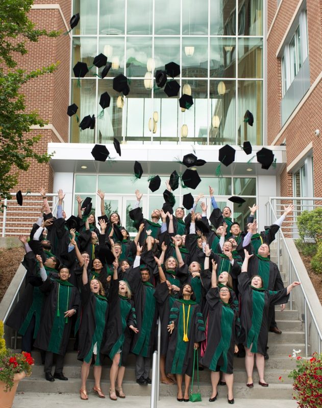 While standing on the steps of the school, members of the Class of 2017 throw their hats in the air in celebration.