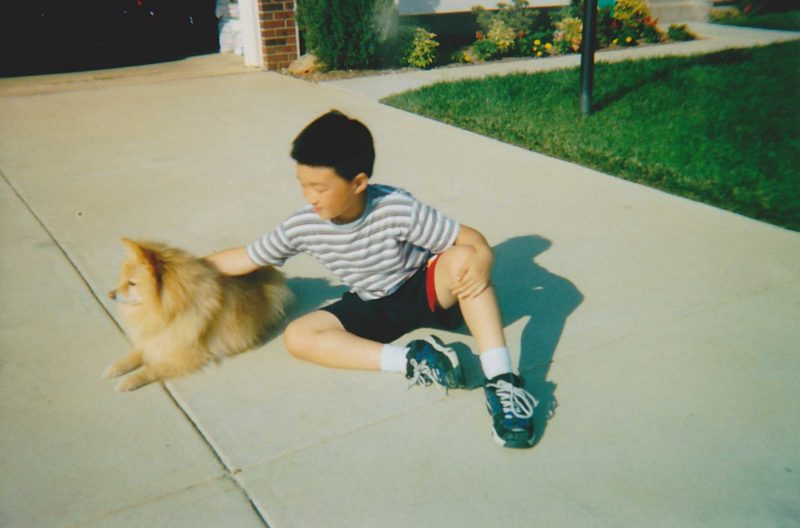 Steve Qian in the driveway with a dog as a child